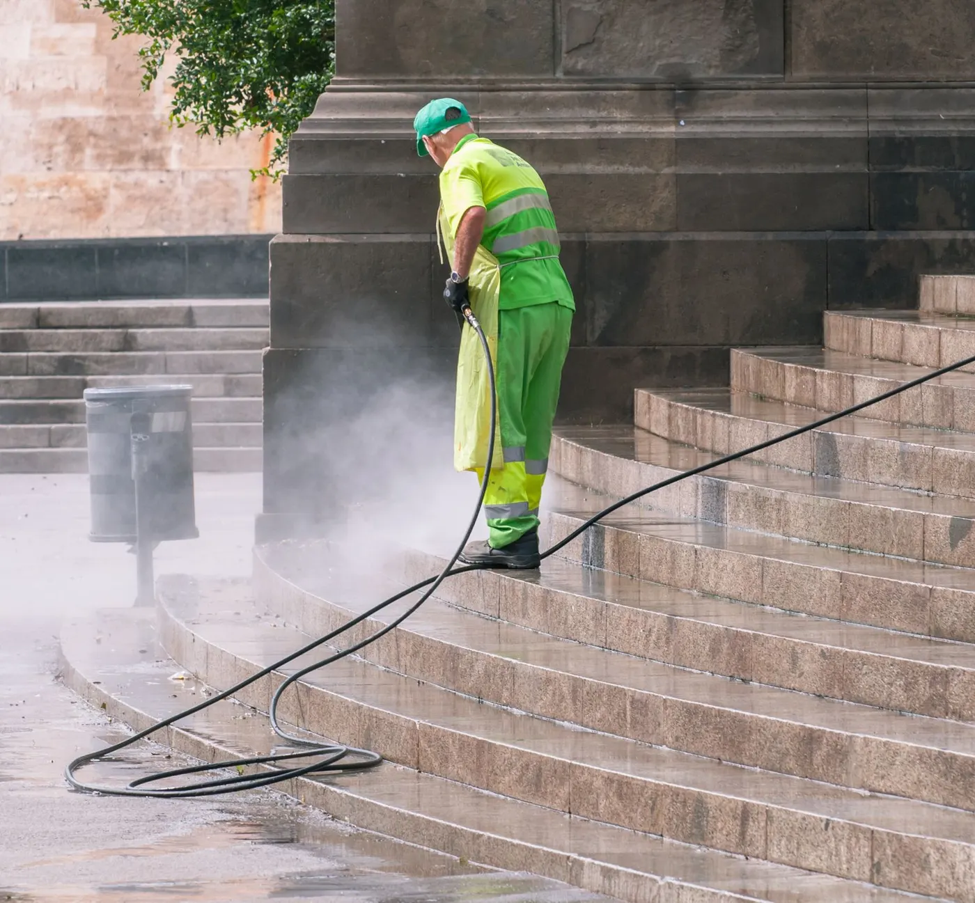 Worker pressure washing paved steps with a high-pressure hose