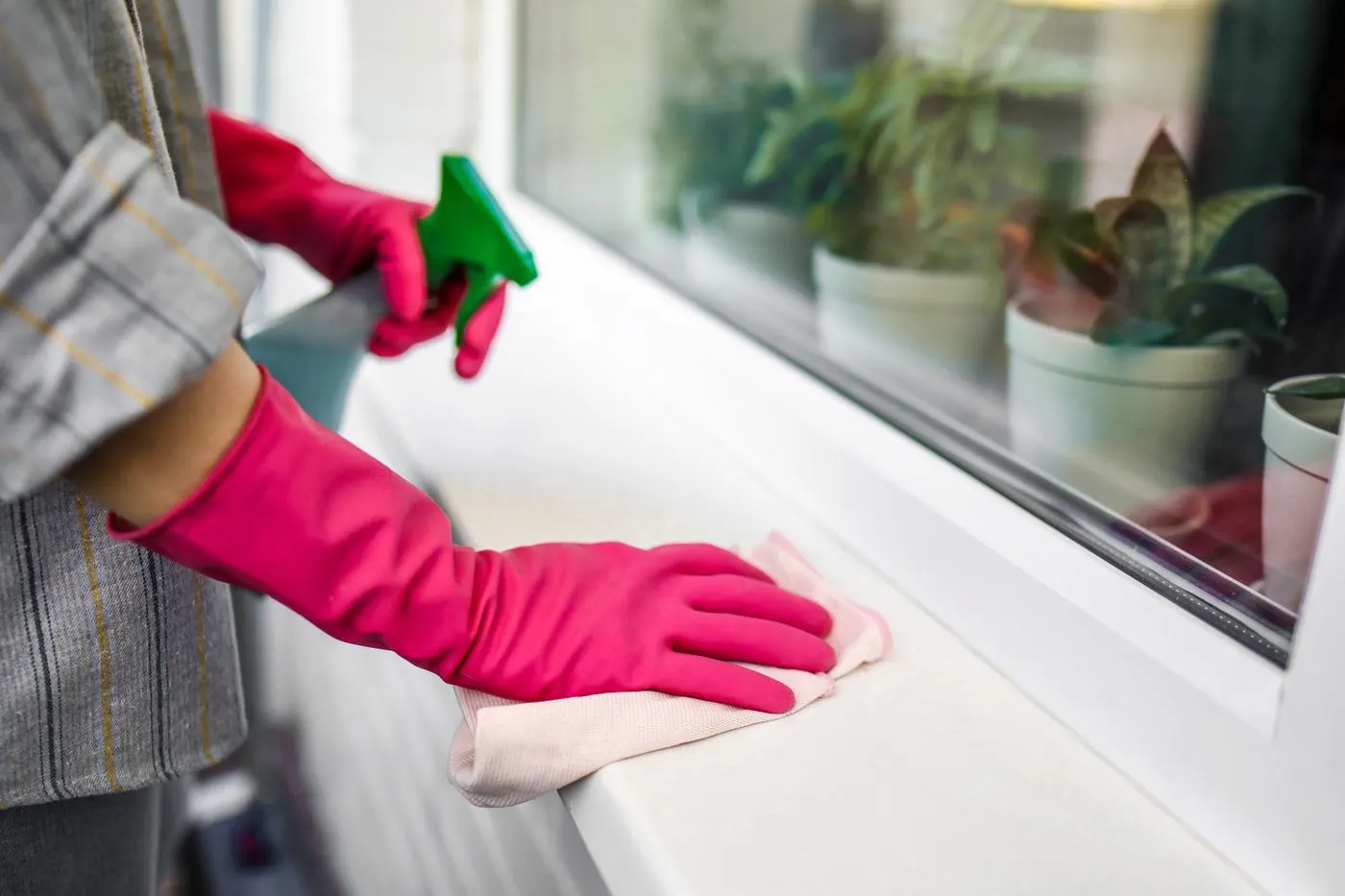 Gloved hand wiping a clean white windowsill