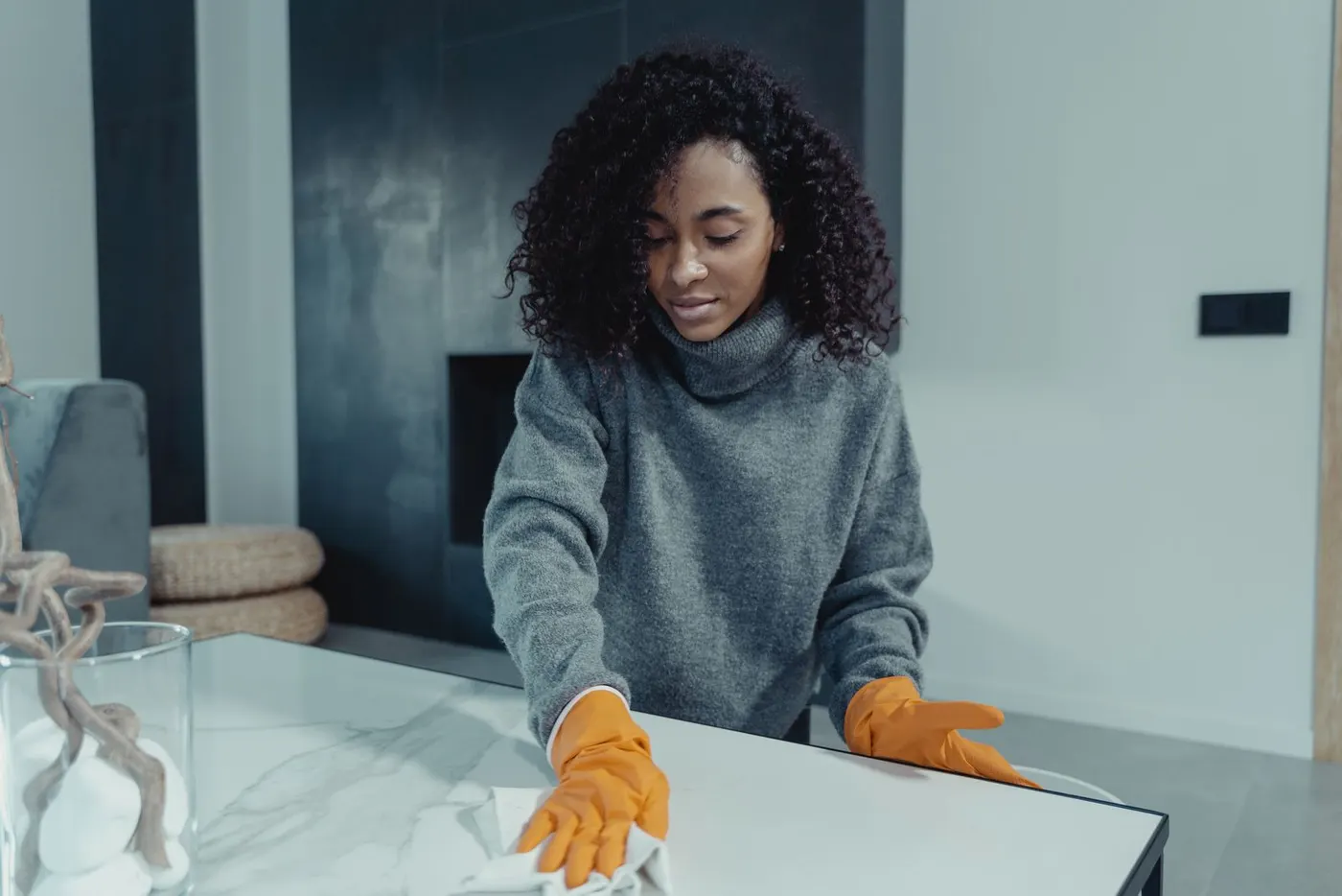 Cleaner wiping a marble kitchen bench with a microfibre cloth
